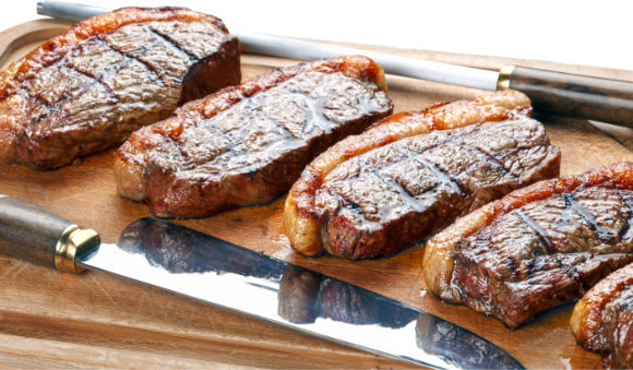 Carne para churrasco: melhores cortes, preparo e organização 1 Cortes de carne para churrasco grelhados, prontos para servir, sobre tábua de madeira.